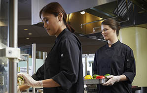 Female chefs in chef coats making and serving wraps